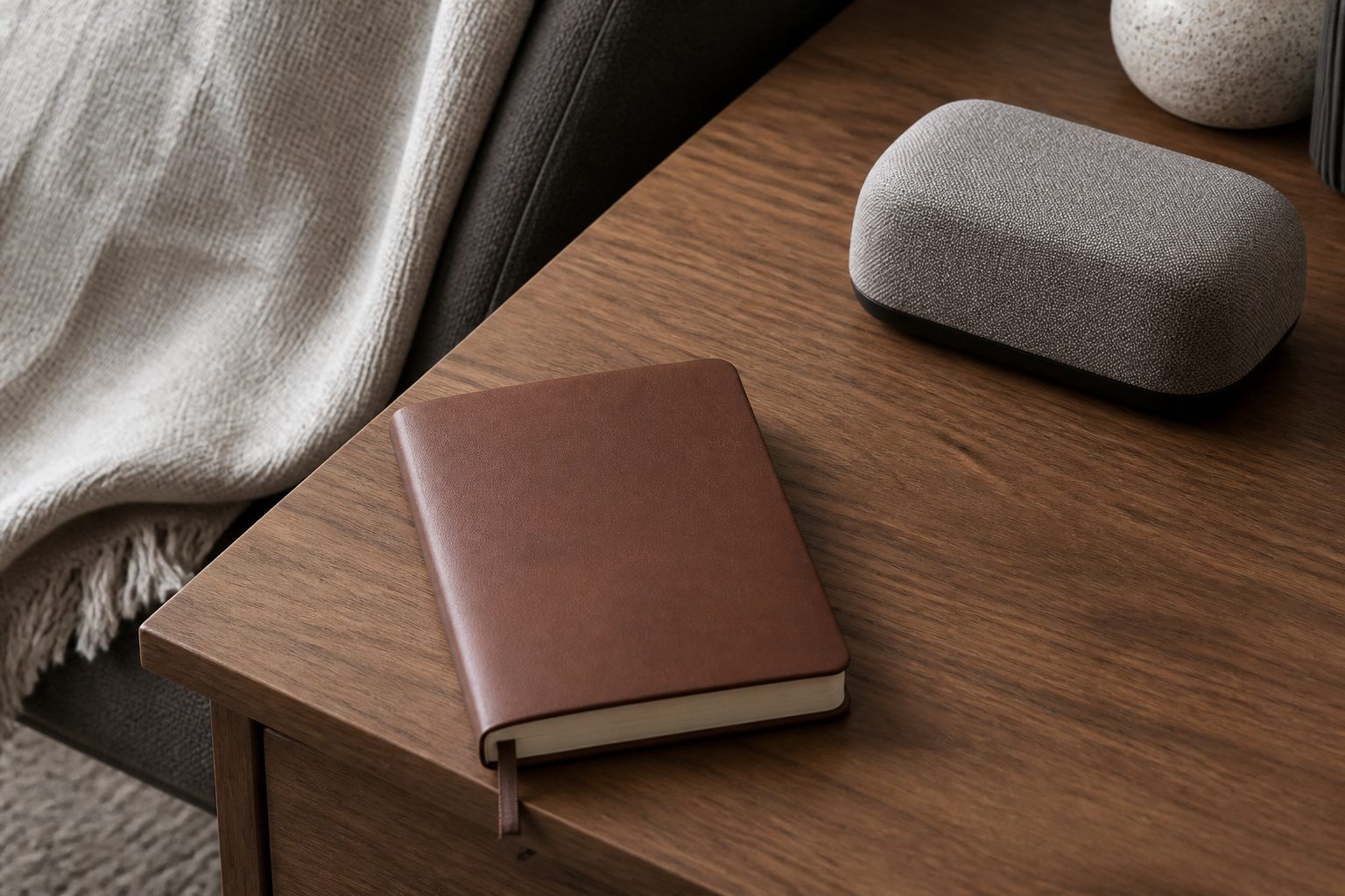 Closed notebook on wood grain with a knit-covered cylinder nearby